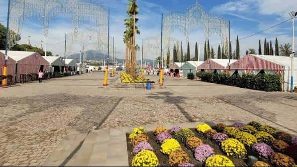Vista diurna del recinto ferial con casetas y decoración floral en primer plano