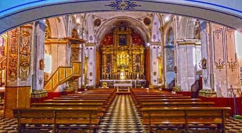 Interior de la iglesia con banco de madera y altar iluminado