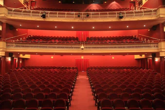 Interior del auditorio con butacas rojas, balcones y cortinas escénicas