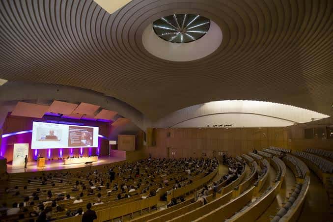 Interior del auditorio principal con aforo completo y escenario iluminado