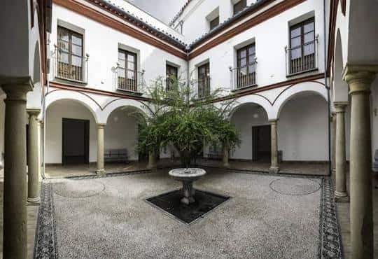Vista del patio central con arcos, columnas y fuente de piedra