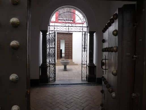 Entrada principal con puerta de madera y reja metálica hacia el patio