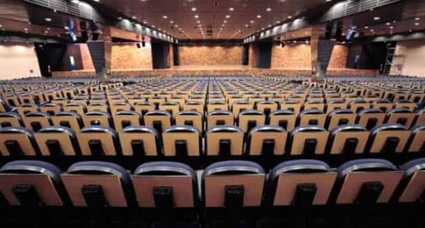 Interior del auditorio principal con filas de asientos y escenario listo para eventos
