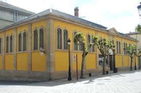 Fachada exterior de la Sala Amós Salvador en Logroño, edificio amarillo con arcos y árboles alineados