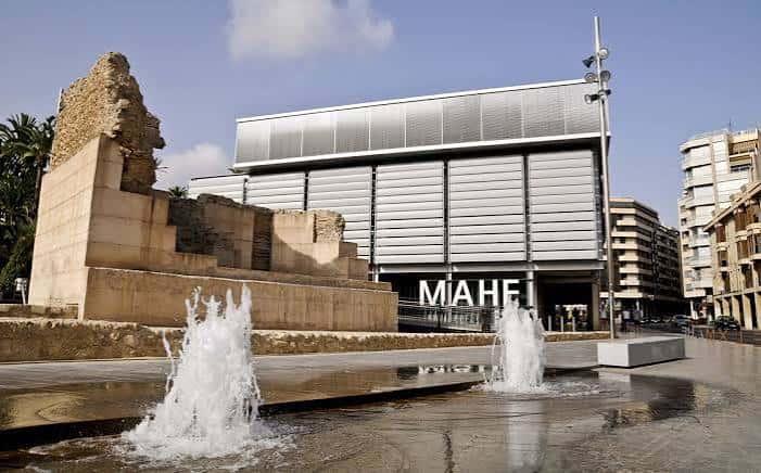 Plaza frontal del MAHE con fuentes activas y ruinas arqueológicas integradas en el paisaje urbano