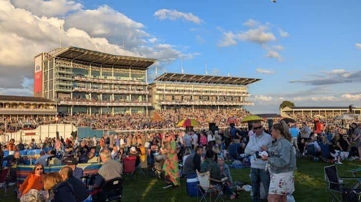Vista panorámica de York Racecourse con multitud de asistentes disfrutando del evento al atardecer