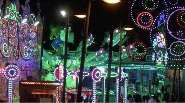 Detalle de las atracciones luminosas y decoraciones festivas en el recinto durante la noche