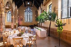 Interior del salón de eventos decorado para una boda con mesas redondas y árboles ornamentales
