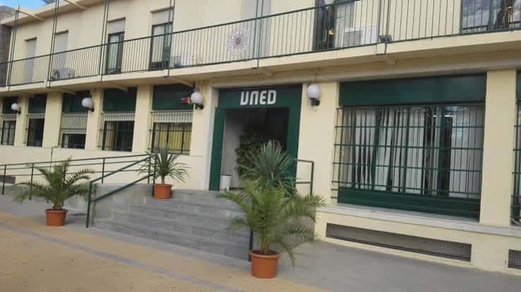Fachada principal de la sede de la UNED en Elche, con entrada accesible y plantas decorativas