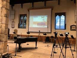 Escenario interior del centro con piano y equipo de proyección listo para eventos