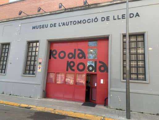 Fachada exterior del Museu de l'Automoció Roda Roda con su distintiva puerta roja y letrero