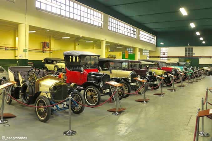 Amplia sala de exposición con múltiples vehículos históricos antiguos alineados en filas
