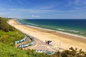 Playa de Bournemouth desde una colina con arena dorada y mar azul bajo cielo despejado