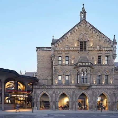 Fachada del teatro al atardecer con iluminación cálida en los arcos de entrada