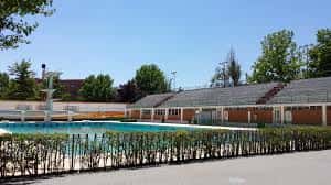 Vista exterior de la piscina olímpica del Complejo Deportivo Carlos Belmonte con césped y árboles al fondo