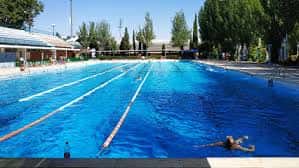 Piscina de natación con nadadores y líneas de carril en un día soleado