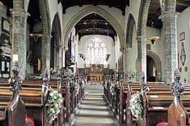 Interior de la iglesia decorado para una boda con arreglos florales en los bancos
