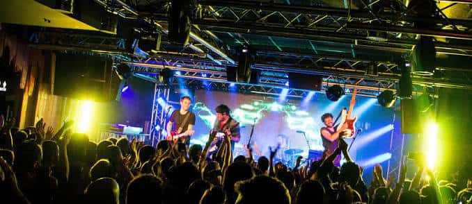 Concierto en vivo en la Sala REM con banda en el escenario y público animado