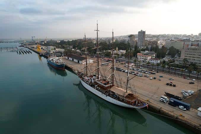 Vista aérea del Puerto de Huelva con un barco histórico atracado y la ciudad al fondo