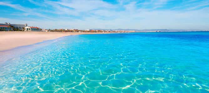 Playa de la Malvarrosa con aguas cristalinas y arena dorada bajo un cielo azul
