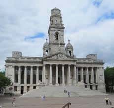 Vista frontal del Portsmouth Guildhall en día nublado con plaza y personas caminando