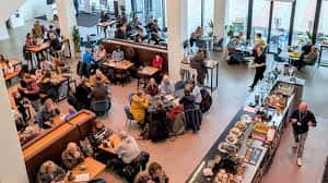 Interior del café-bar del The Box con clientes sentados en mesas y mostrador de comida