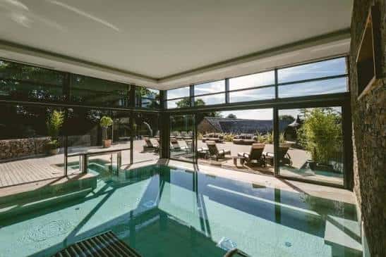 Piscina interior del spa con grandes ventanales y vistas al exterior