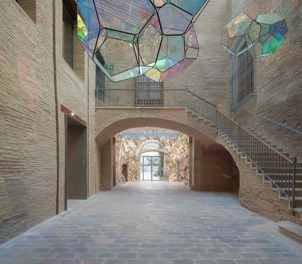 Patio interior con escalera de ladrillo y escultura de vidrio multicolor
