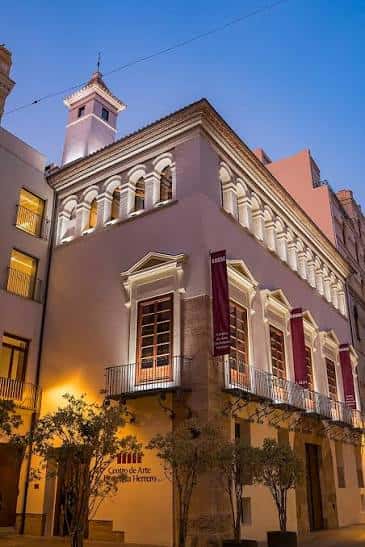 Fachada iluminada del centro al atardecer con letrero visible