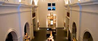 Vista panorámica del hall principal del museo con iluminación cálida y vitrinas centrales