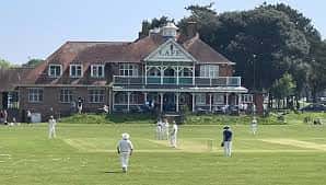 Partido de cricket en los campos de Kings Park con el club house al fondo