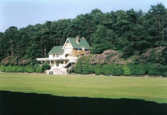 Vista panorámica del campo deportivo y el edificio principal de Meyrick Park rodeado de bosque