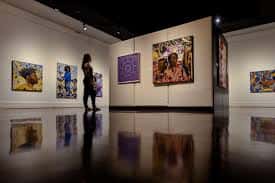 Interior de una sala de exposiciones con obras de arte contemporáneo en las paredes y un visitante contemplando la colección, ideal para eventos culturales