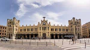 Fachada completa de la Estación del Norte con arquitectura modernista valenciana y cielo parcialmente nublado