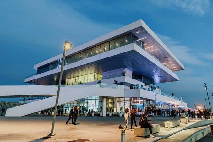 Fachada moderna del centro de eventos con personas caminando en la plaza