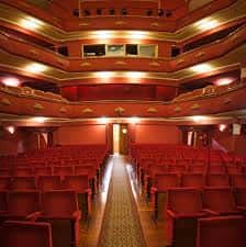 Interior del auditorio del Teatro Talía con butacas rojas, balcones y escenario con cortina roja