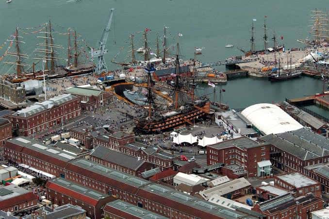 Vista panorámica del puerto histórico con múltiples barcos de vela y edificios de ladrillo