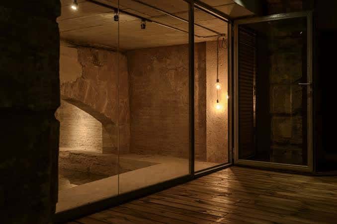 Interior moderno del Celler de Proava con paredes de piedra y suelo de madera