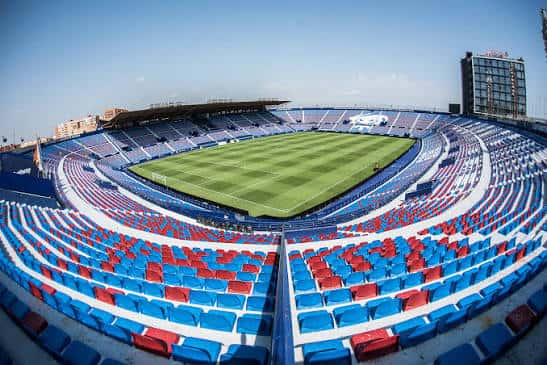 Vista panorámica del interior del Estadio Ciutat de València con gradas vacías y campo de césped bajo luz diurna