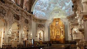 Interior de la iglesia con altar dorado y bóveda pintada