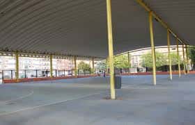 Interior del polideportivo con estructura metálica y suelo deportivo