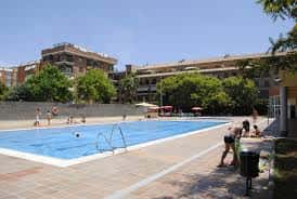 Piscina exterior del complejo deportivo con personas disfrutando del sol