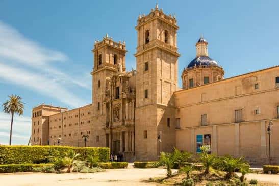 Vista frontal del Monasterio de San Miguel de los Reyes con su fachada barroca y torres gemelas bajo un cielo azul