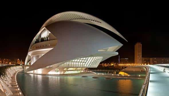Vista nocturna del Palau de les Arts Reina Sofía con iluminación dramática y reflejos en el agua