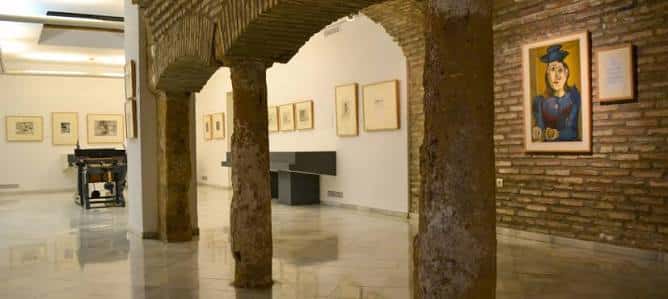 Interior del museo con arcos de ladrillo y obras de grabado expuestas