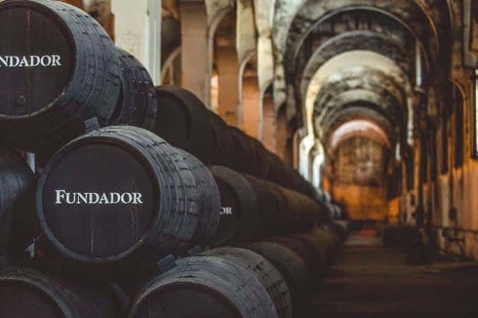 Pasillo de barricas con el logo Fundador en un interior de bodega
