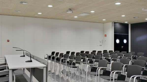 Sala de reuniones con mesas y sillas dispuestas para presentación