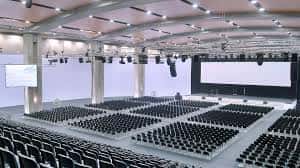 Salón de eventos interior con disposición de butacas y escenario listo para conferencias o exposiciones