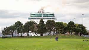 Área verde del Mayflower Park con el edificio circular en el fondo