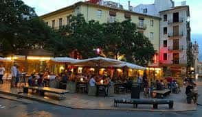 Plaza del Tossal al atardecer con terrazas de cafeterías llenas de gente, ideal para eventos sociales